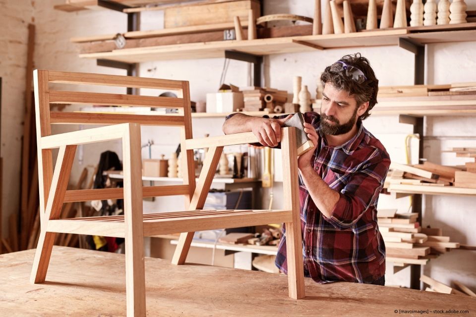 Ein Mann arbeitet in einer Werkstatt an einem Holzstuhl.