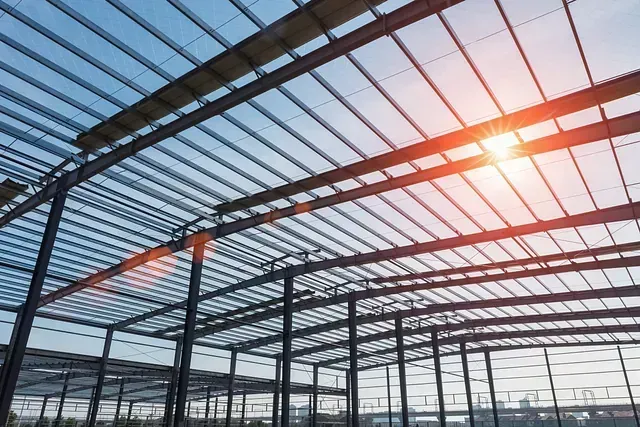 Estructura de acero de un edificio en construcción, con el sol brillando a través del techo sin terminar.