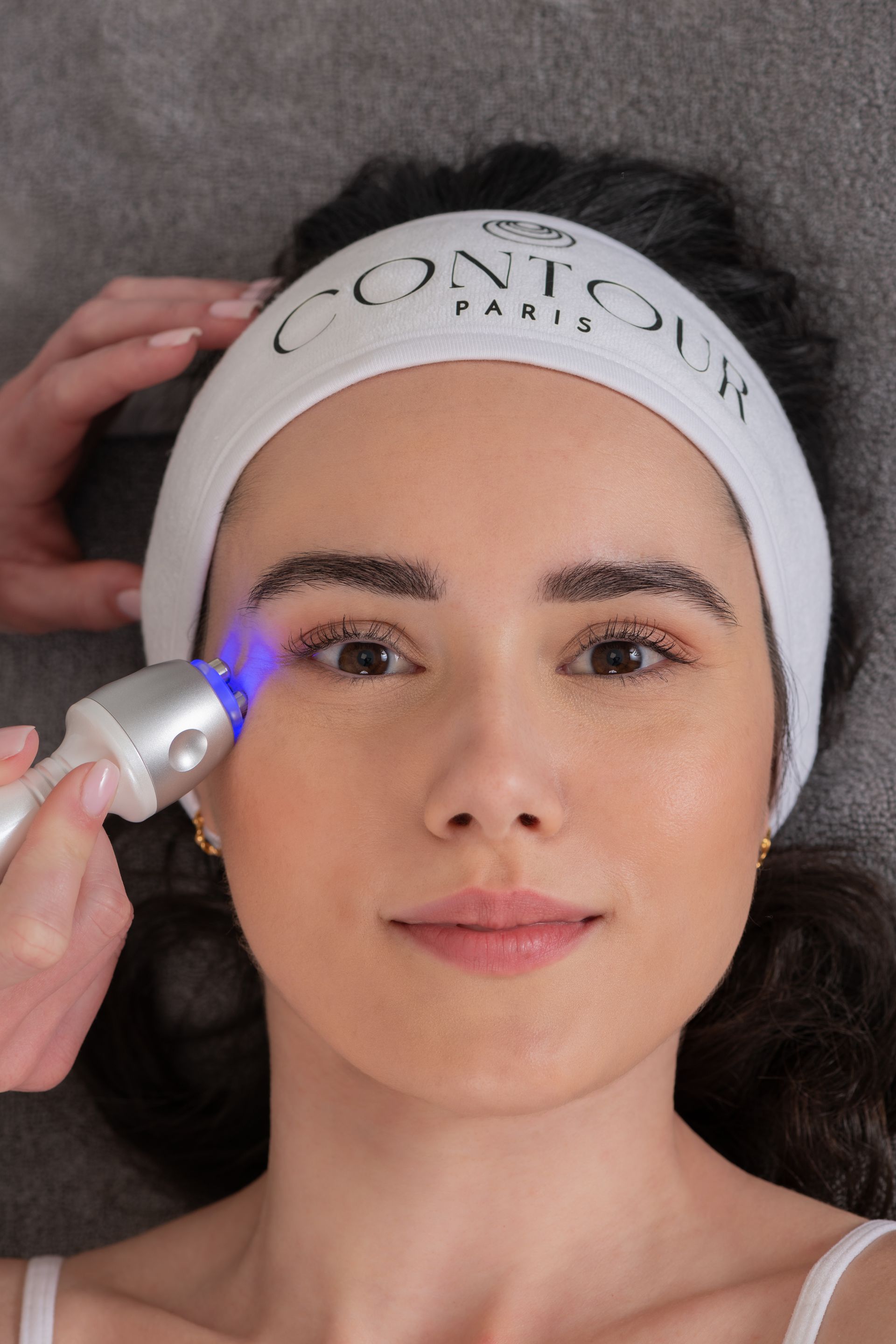 Personne portant un bandeau blanc et recevant un soin du visage.