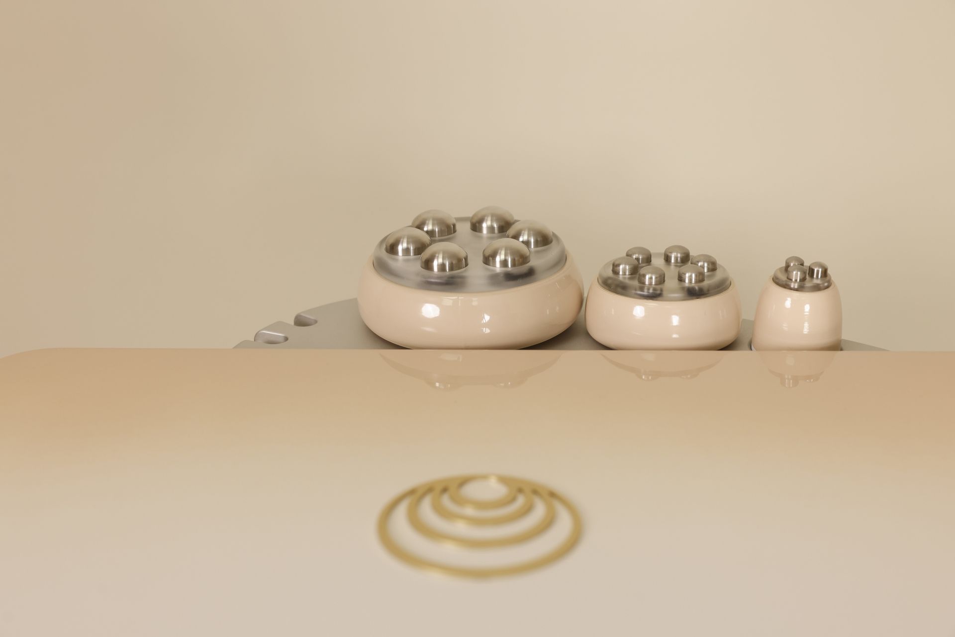 Trois embouts de radiofréquence beiges ornés de sphères argentées.