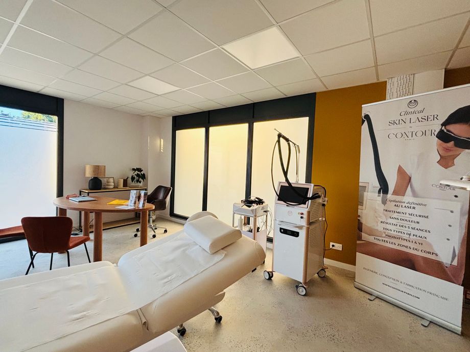 Salle de soins médicoesthétiques avec une table, du matériel médical et une affiche publicitaire.