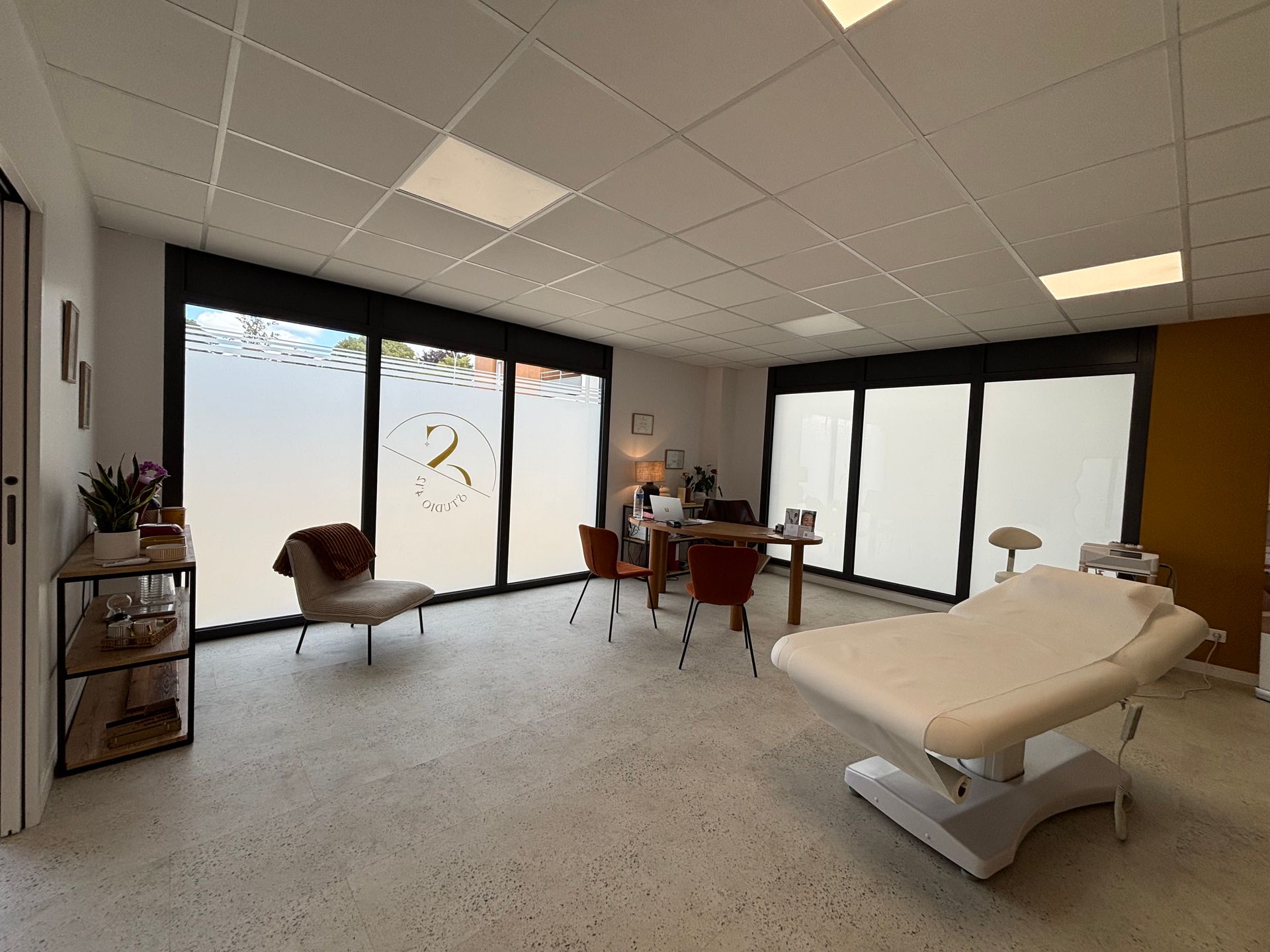 Salle du Studio 4'12 avec table de soins, bureau, chaises.