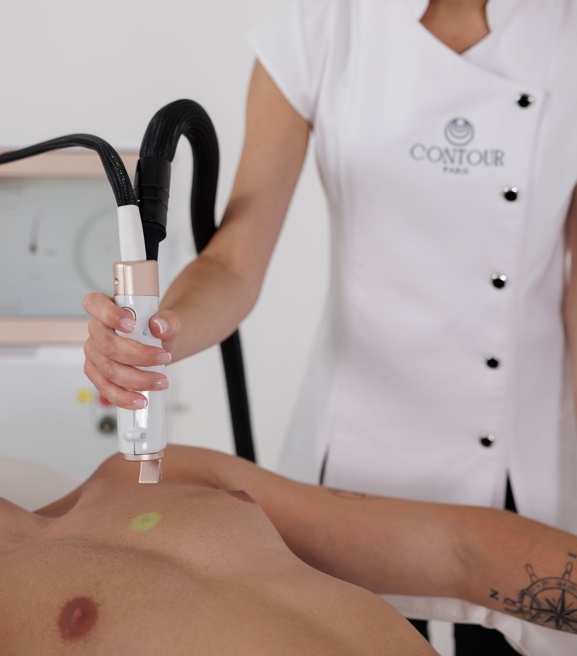 Une praticienne utilise un appareil d'épilation laser sur la poitrine d'une personne.