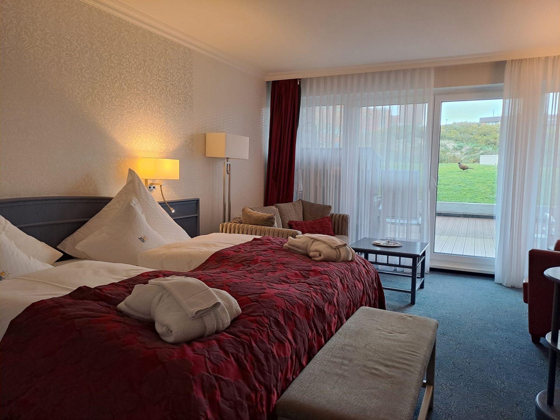 Ein Hotelzimmer mit zwei Betten, einer Bank, einem Stuhl und einem Tisch.