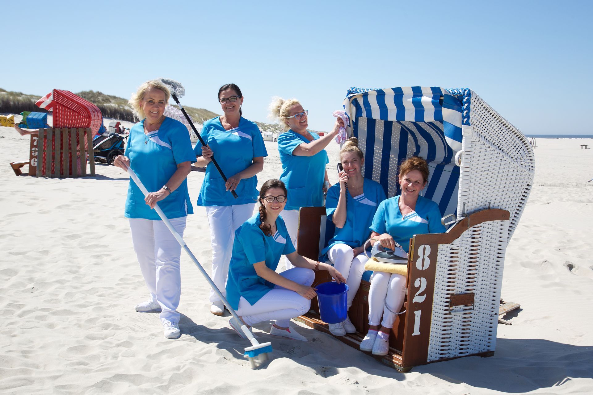 Eine Gruppe von Frauen reinigt einen Strandstuhl am Strand.