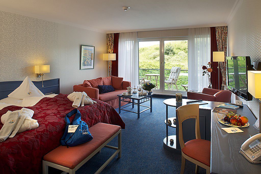 Ein Hotelzimmer mit einem großen Bett und einer Couch, Blick in die Dünen