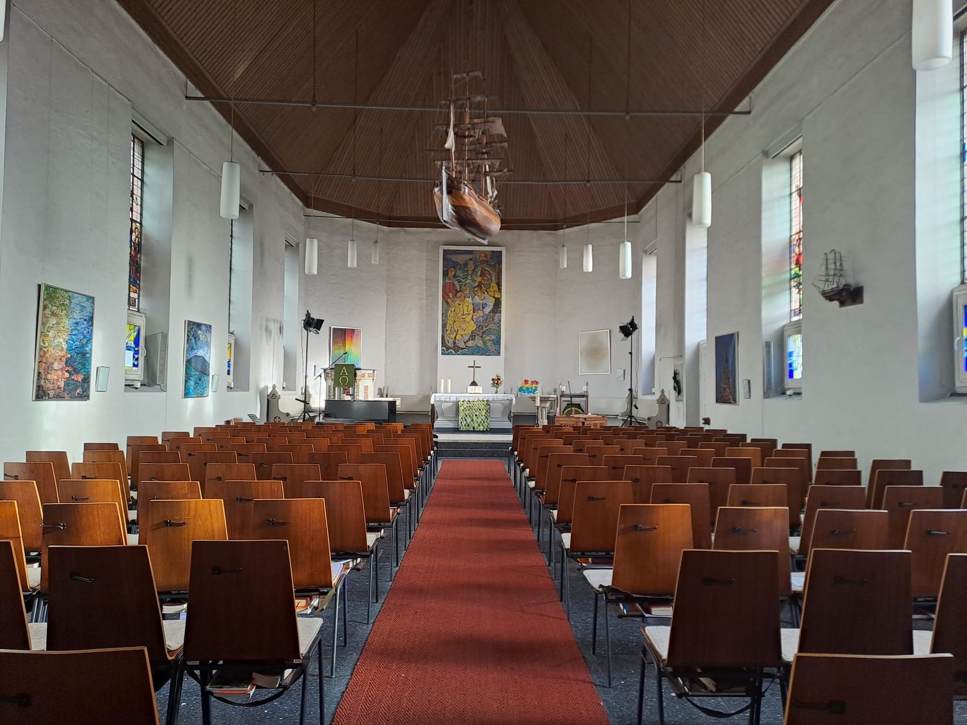 Eine Kirche mit Reihen von Holzstühlen und einem roten Teppich