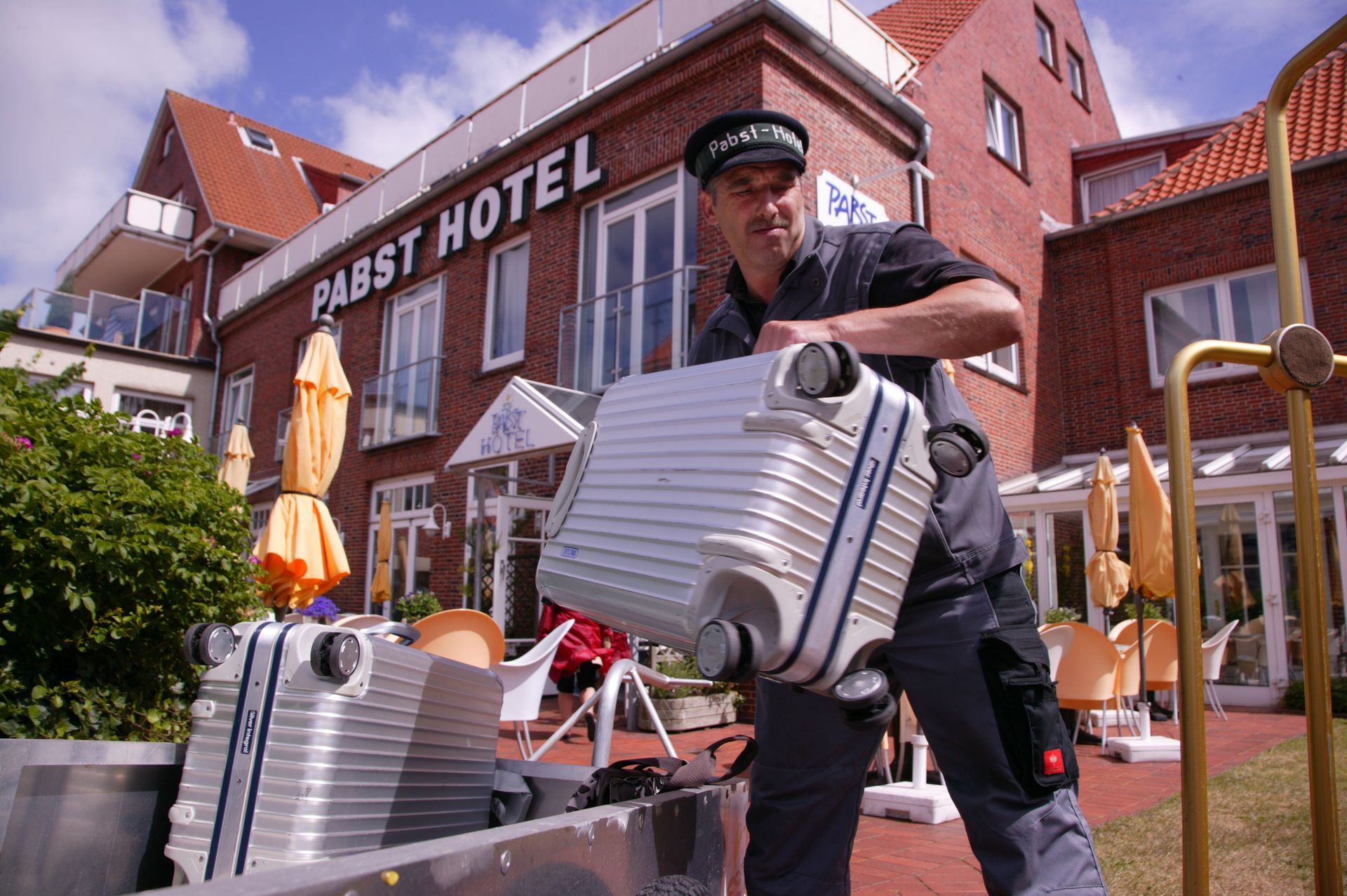 Ein Mann trägt einen Koffer vor einem Hotel.