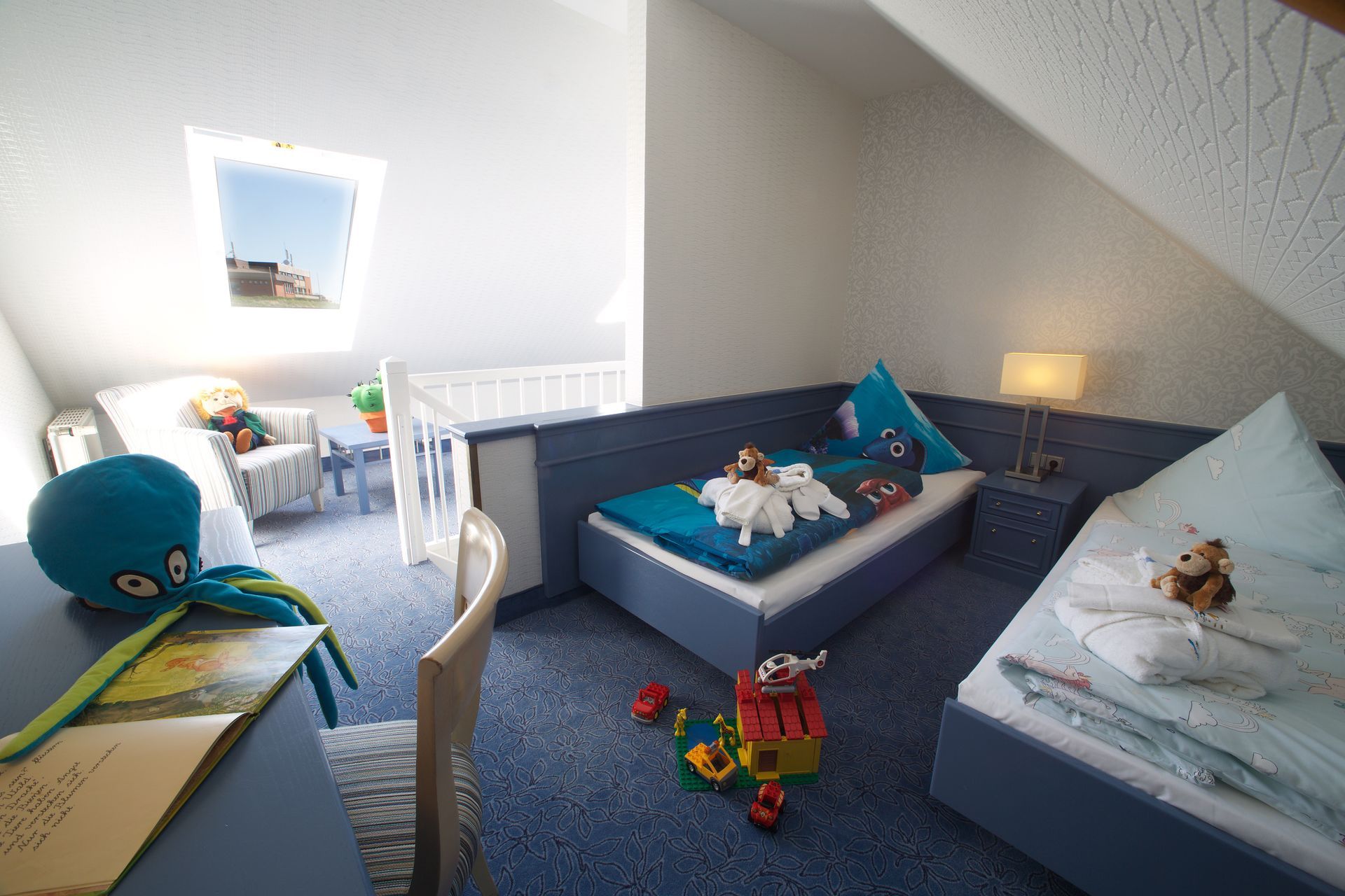 Ein Schlafzimmer mit zwei Betten, einem Schreibtisch und Kinderspielzeug.