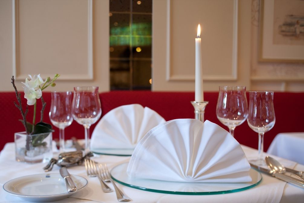 Auf einem Tisch in einem Restaurant brennt eine Kerze und sorgt für stimmungsvolle Atmosphäre.