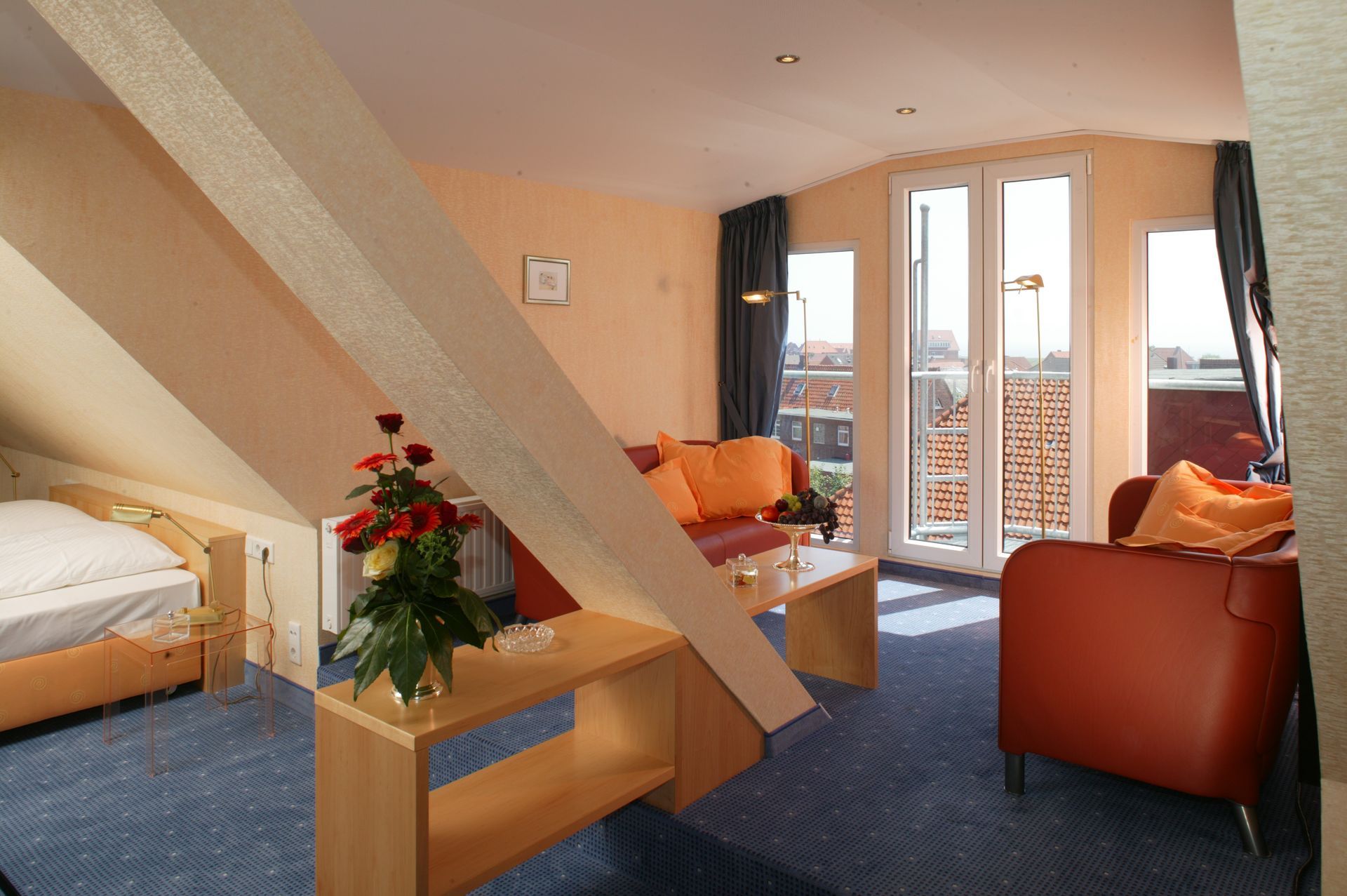 Ein Wohnzimmer mit Bett, Couch, Sessel und Tisch.