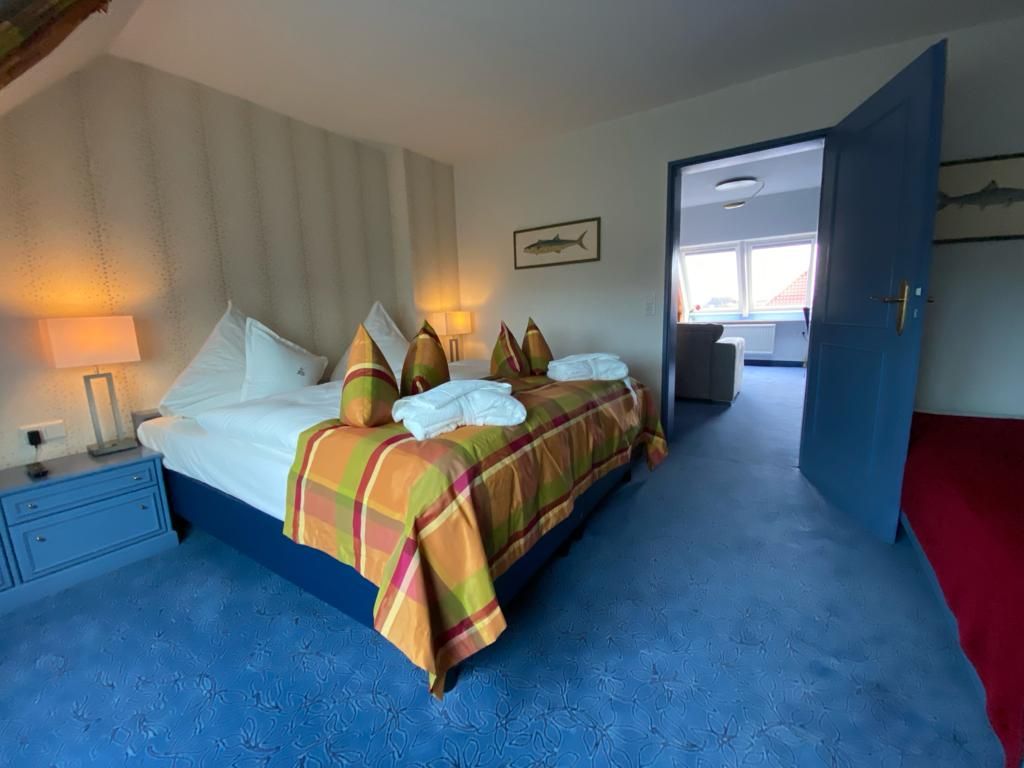 Ein Hotelzimmer mit einem großen Bett und einem blauen Teppich. Eltern-Schlafzimmer Familiensuite.