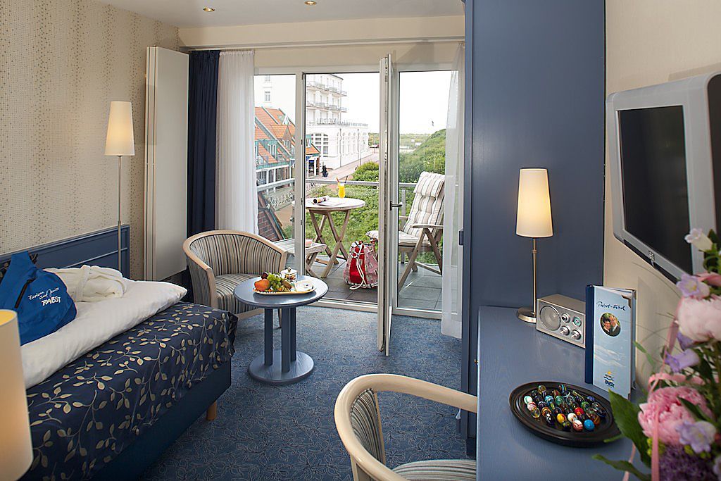 Ein Hotelzimmer mit Bett, Schreibtisch, Stuhl und Fernseher