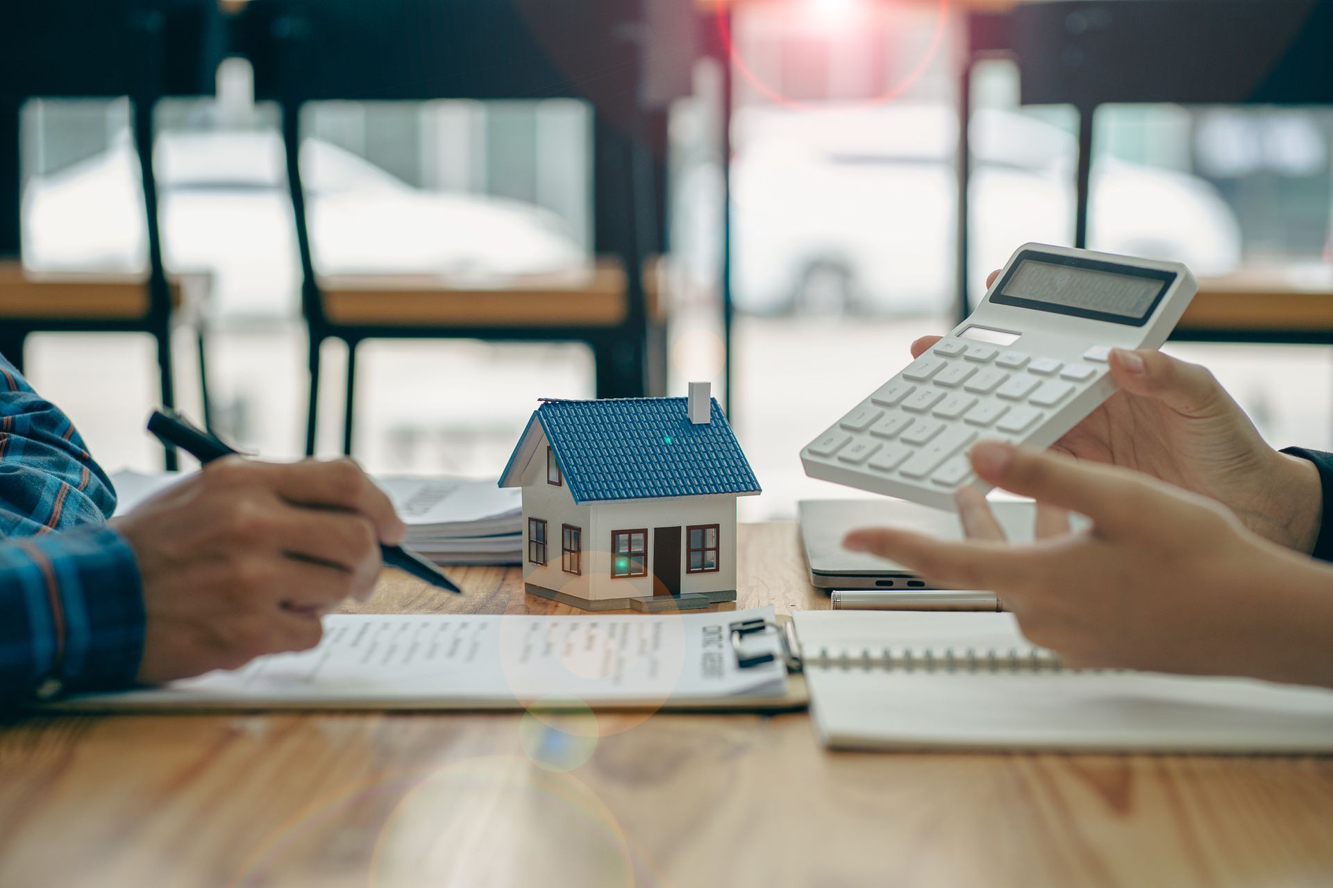 Photo de mains avec un contrat signé et une calculatrice pour une transaction immobilière