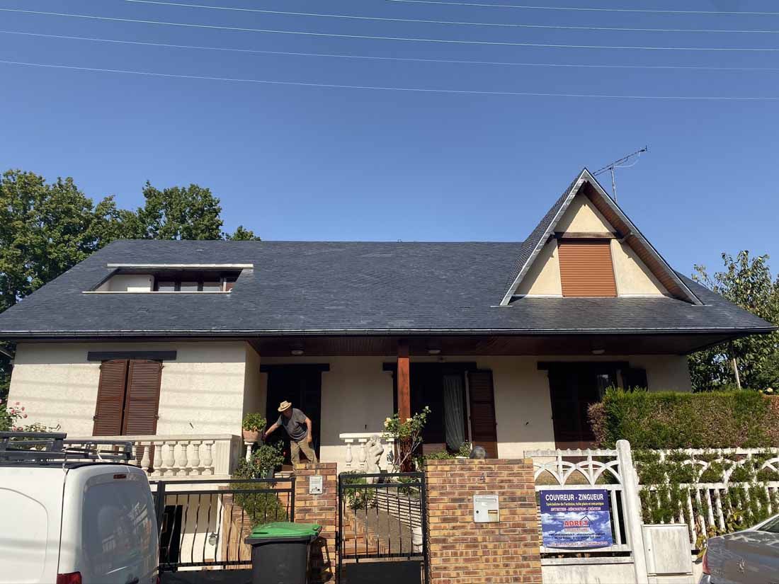 Un homme sort d'une maison avec un toit en ardoise