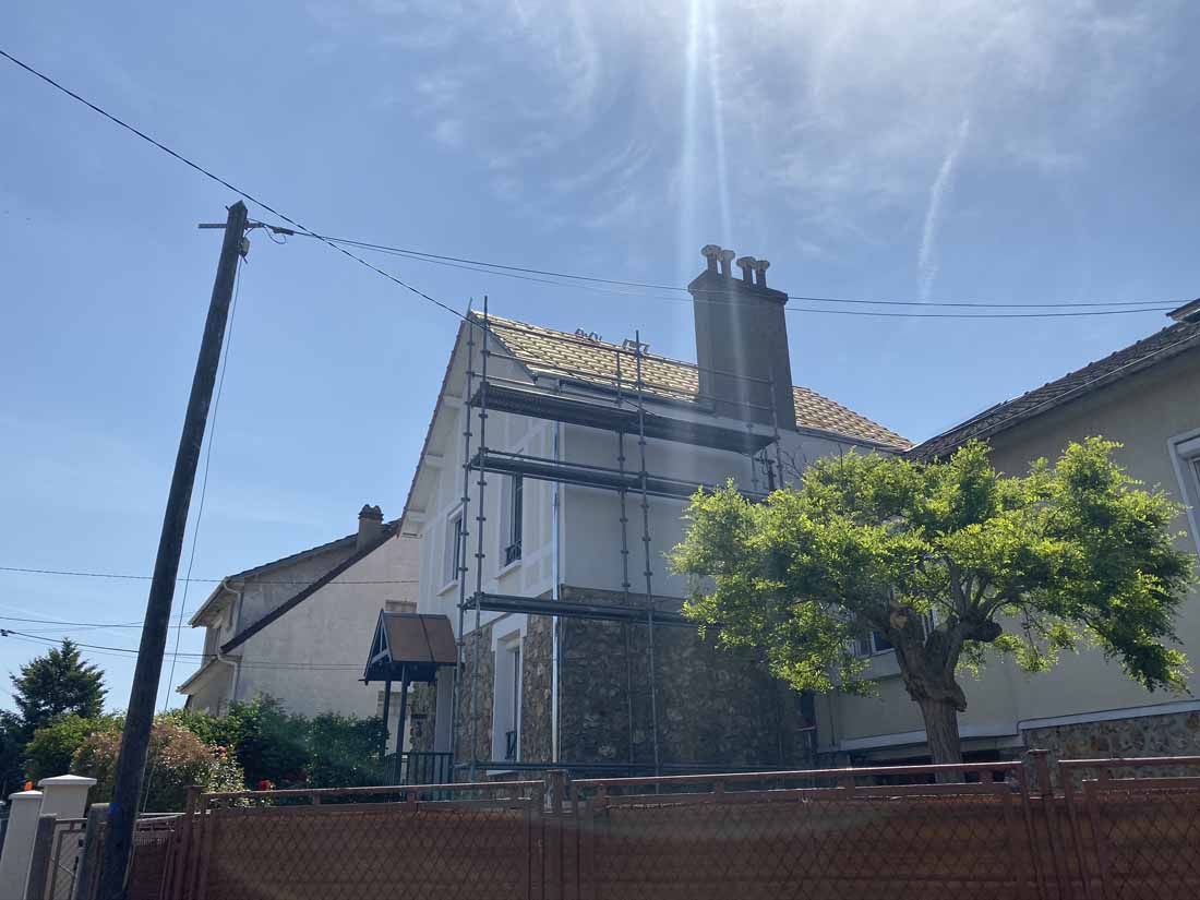 Un échafaudage sur la façade d'une maison avec une cheminée