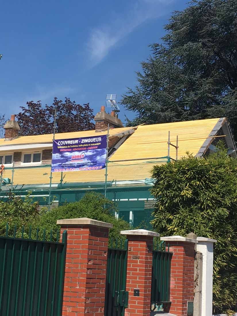 Panneau de l'entreprise Adret Couverture devant une charpente de toit