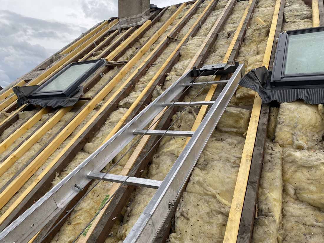 Une charpente de toit apparente, une échelle et deux fenêtres de toit