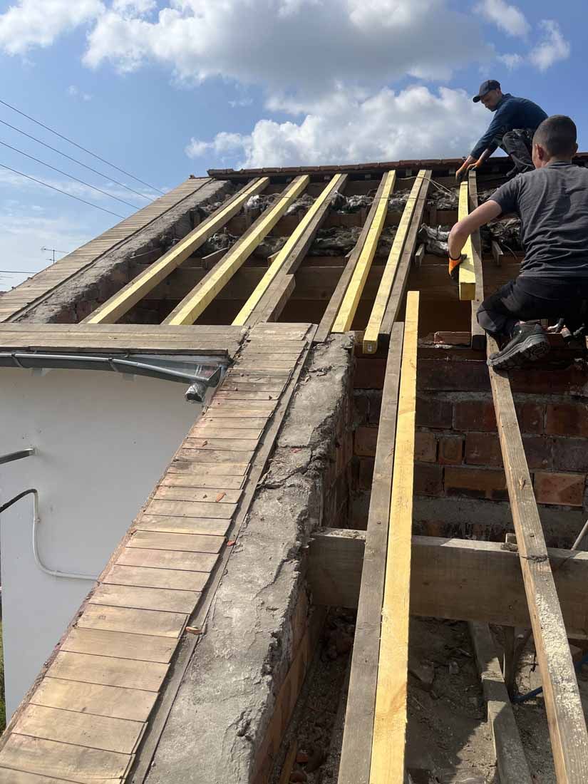 Deux ouvriers s'occupent d'une charpente de toit