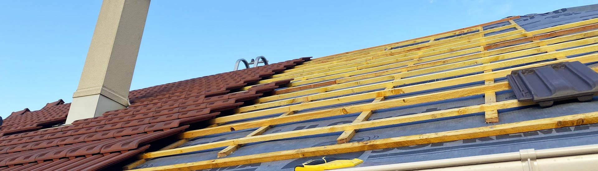 Une toiture en train d'être recouverte par des tuiles