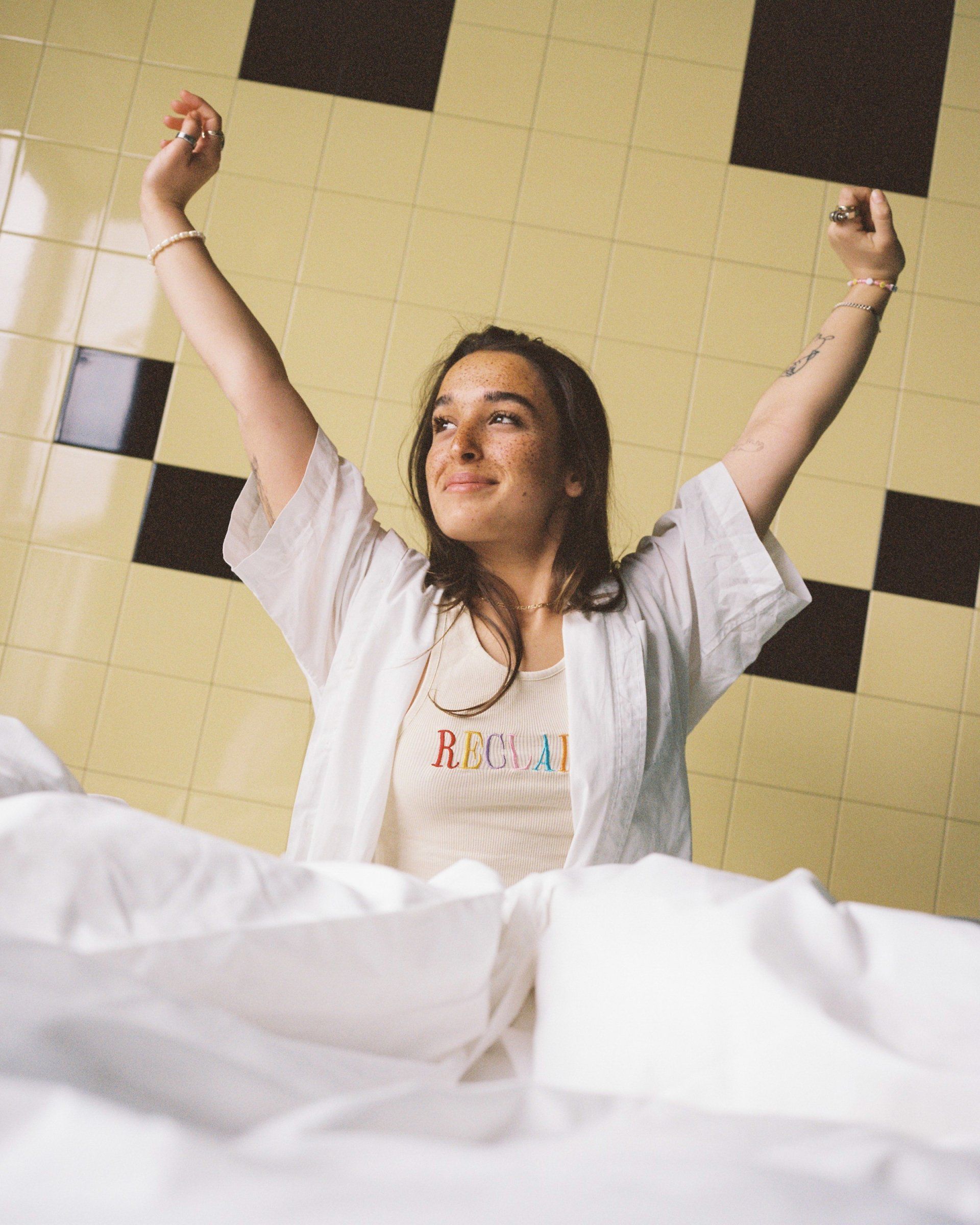 Gerade aufgewachte Person streckt sich entspannt im Bett nach dem Schlaf