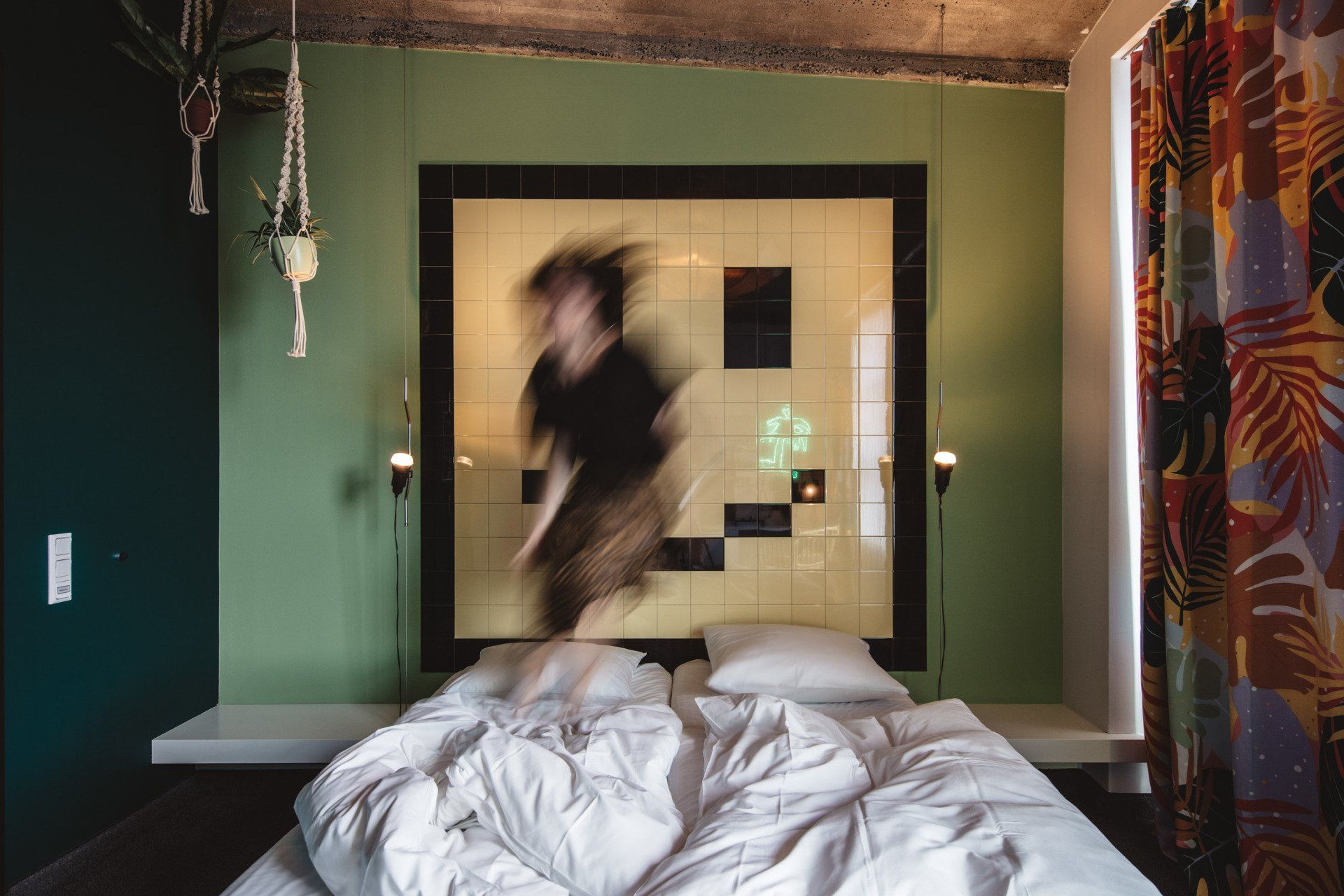 Springende Person auf einem Hotelbett, die Bettwäsche ist leicht verwuschelt