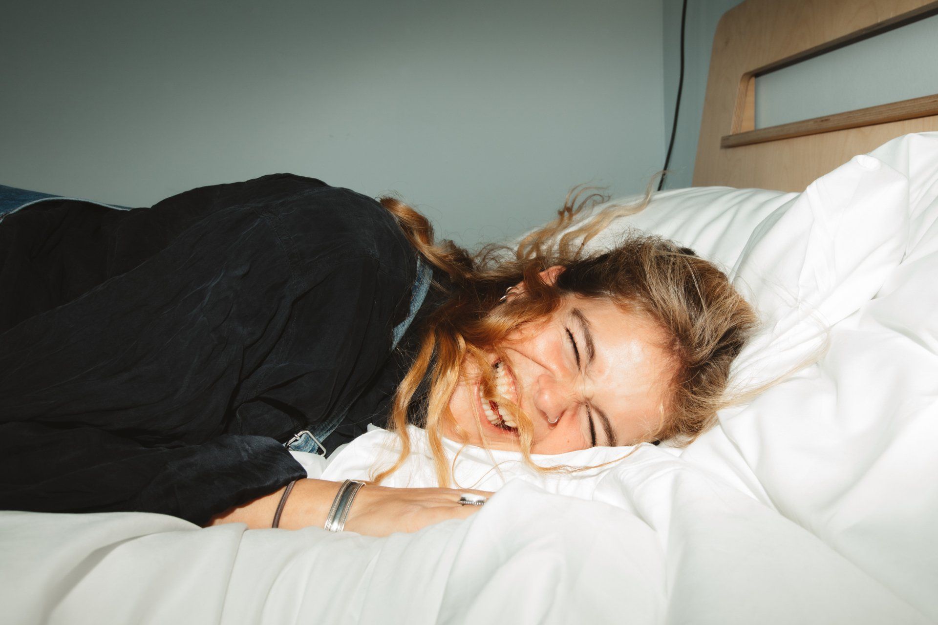 Weiblich gelesene Person liegt mit dem Kopf auf einem weißen Kopfkissen im Bett