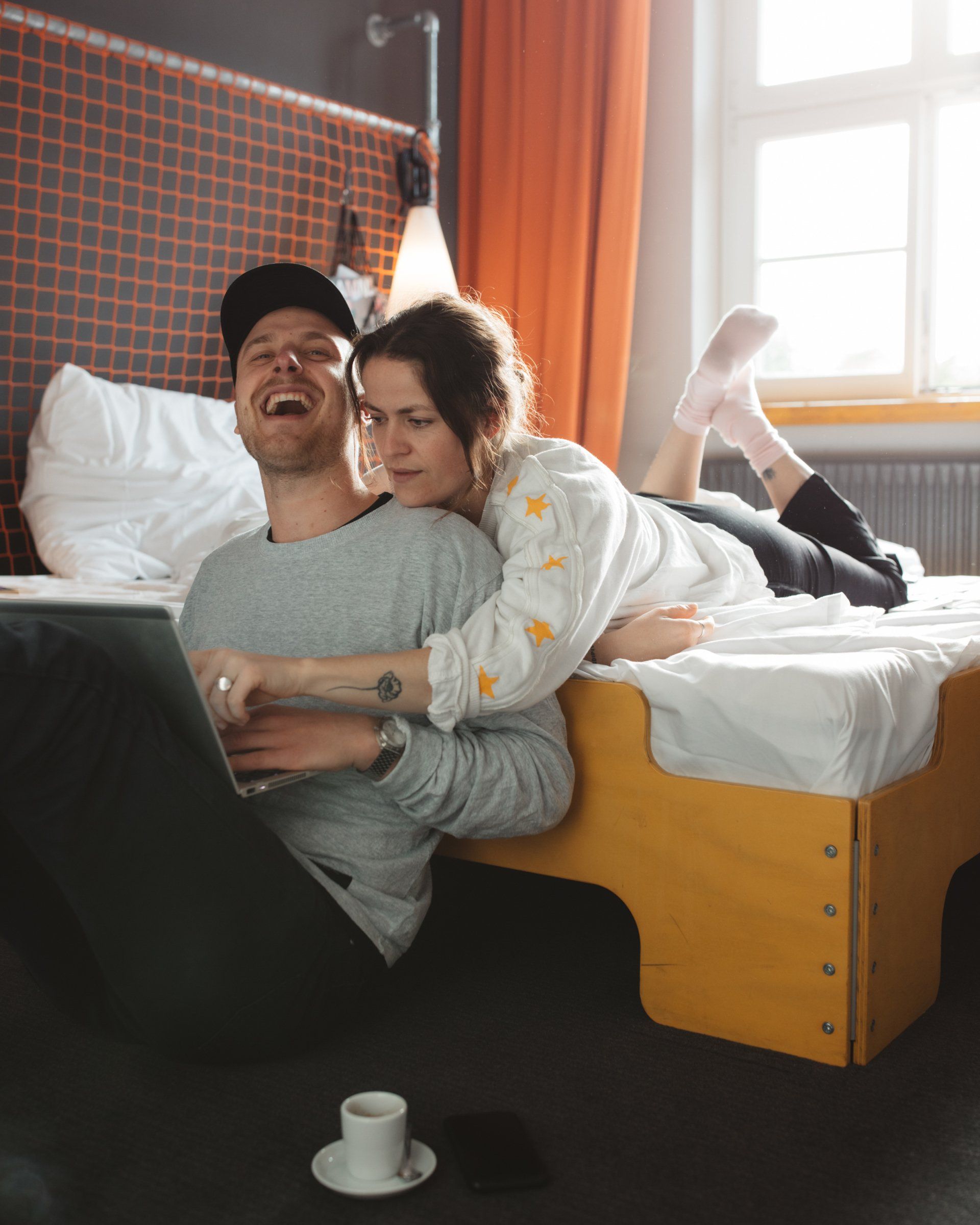 Personenpaar auf einem Bett in gemütlicher Atmosphäre eines Hotelzimmers