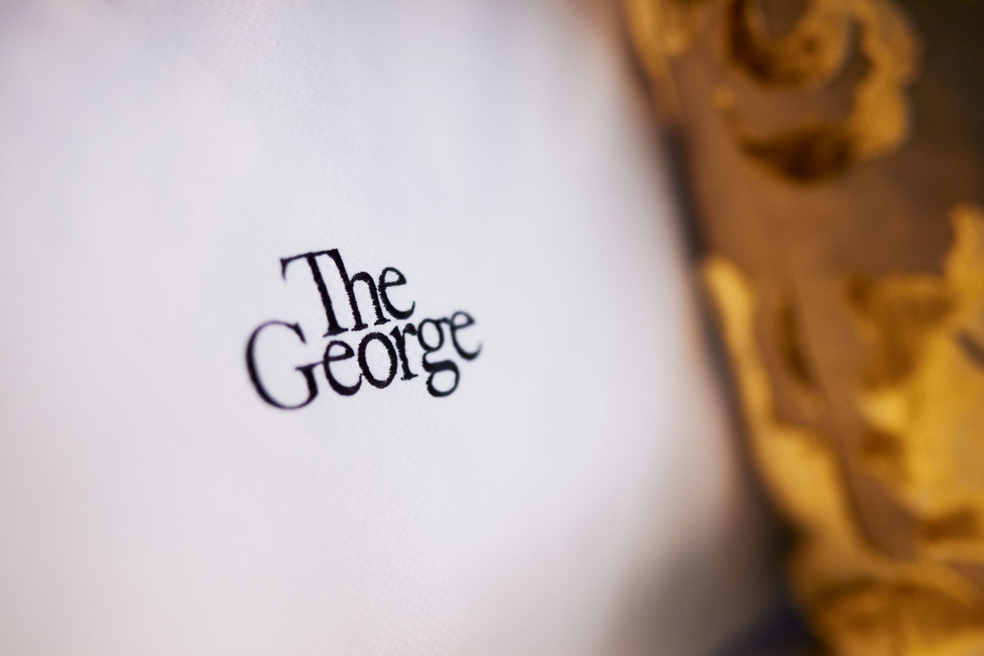 Nachaufnahme eines Kissens mit dem The George Logo