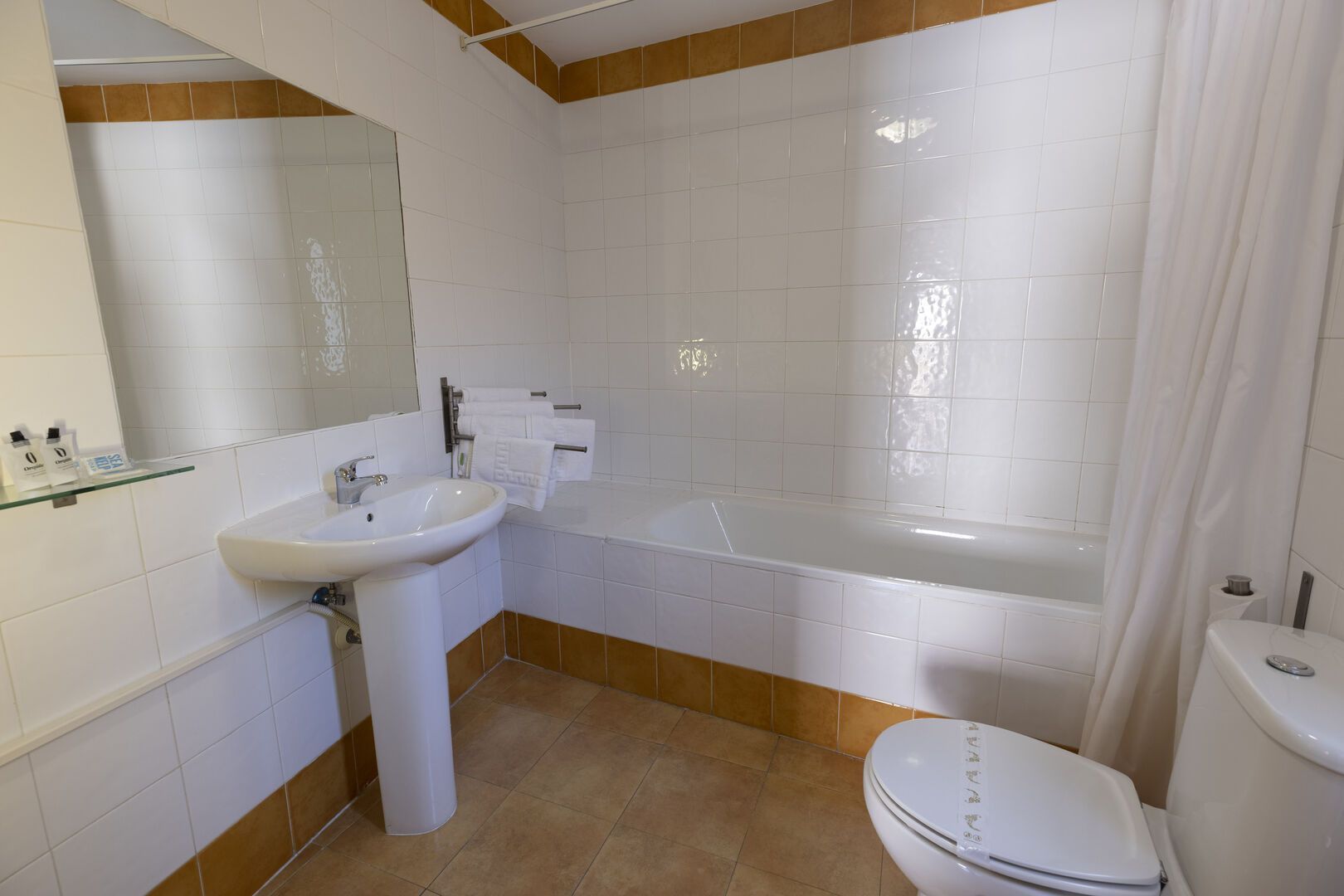 Un baño con lavabo, inodoro, bañera y espejo.