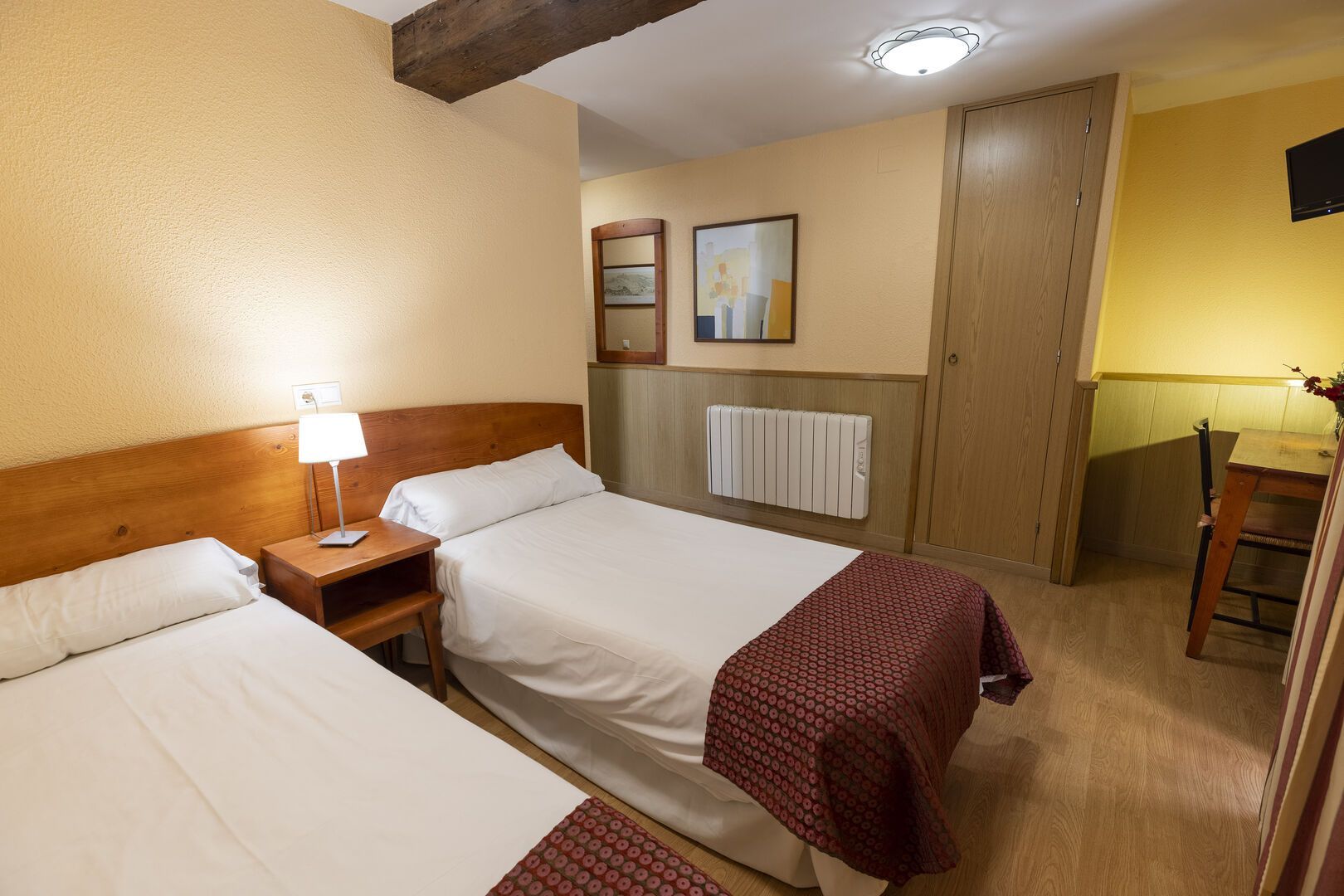 Una habitación de hotel con dos camas, un escritorio y un televisor.