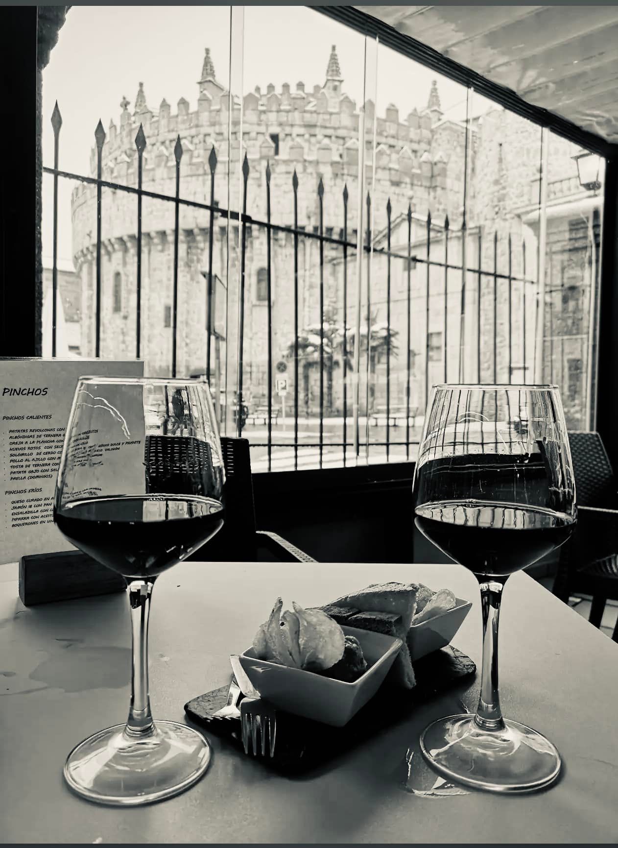 Una fotografía en blanco y negro de dos copas de vino sobre una mesa.