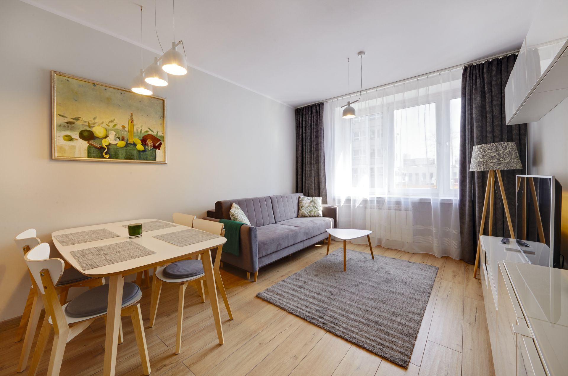 Salon moderne avec canapé, table à manger, grande fenêtre et décoration neutre.