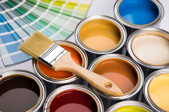 Pinceau posé sur des pots de peinture ouverts, avec des échantillons.