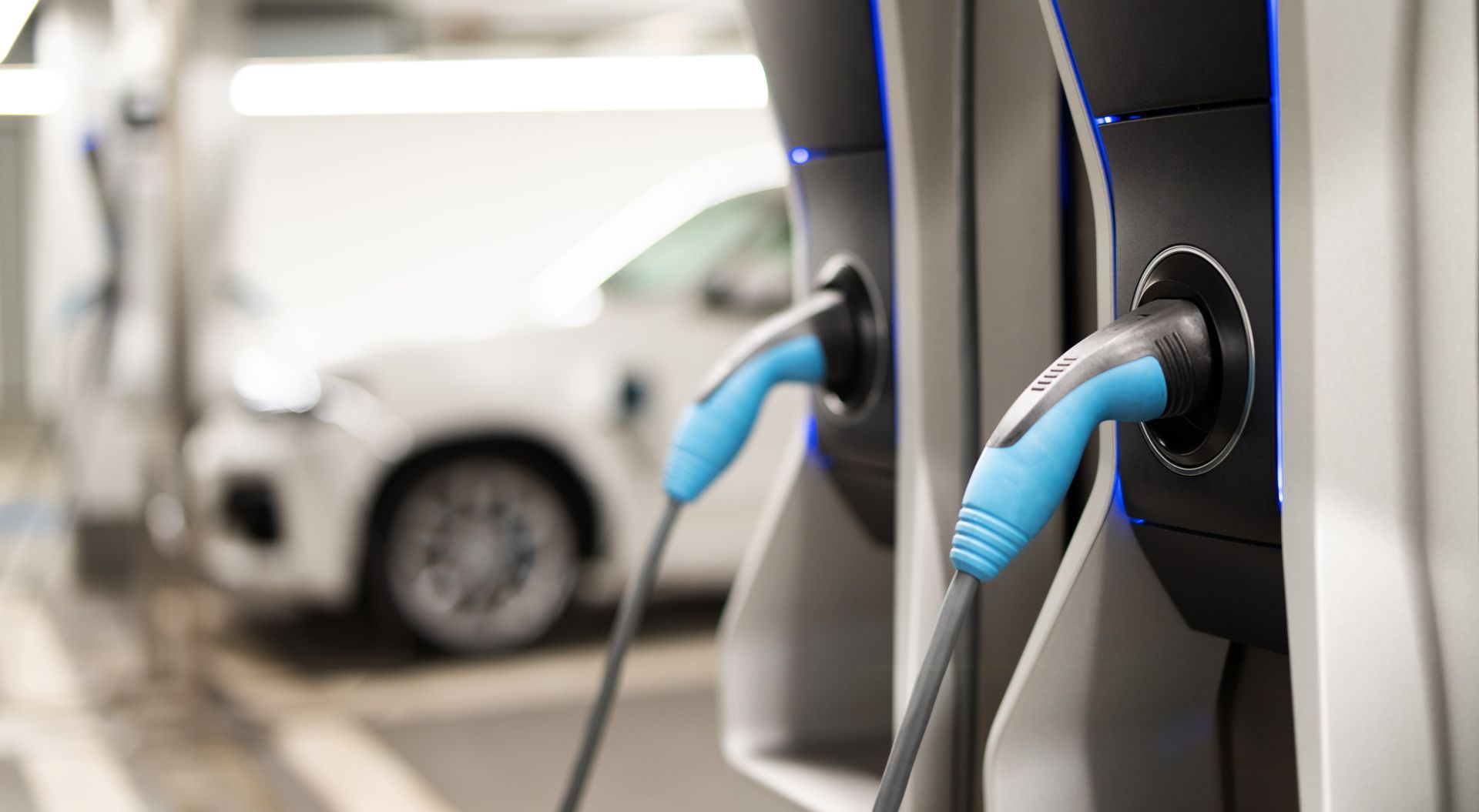Des prises pour véhicules électriques sont connectées à deux bornes de recharge dans un garage.