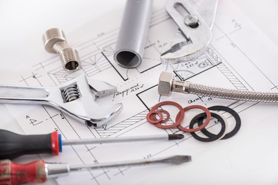 Divers outils et raccords de plomberie figurant sur les plans, notamment des clés, des tuyaux et des rondelles.
