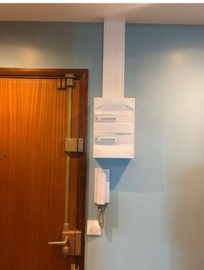 Mur d'un couloir avec un boîtier de commande fixé à côté d'une porte en bois sur un mur.