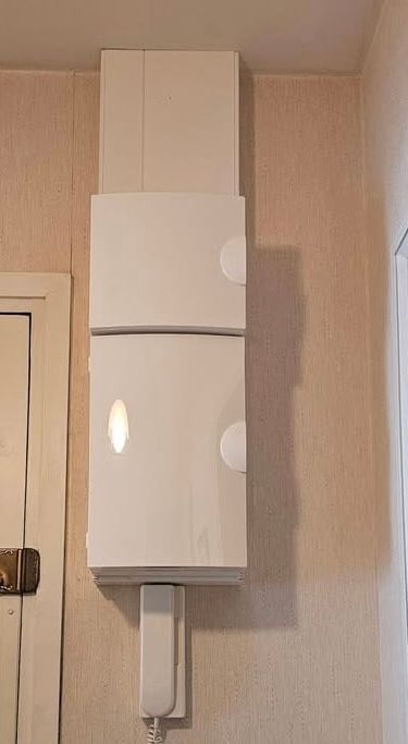 Armoire murale ou chaudière avec un tuyau, sur un mur intérieur près d'une porte.