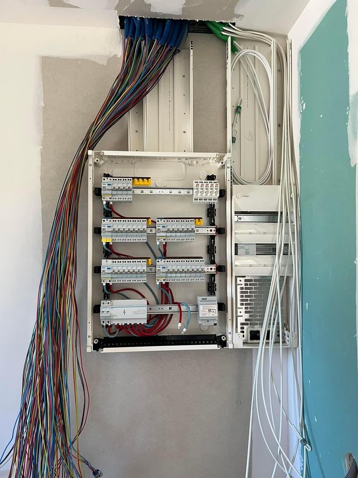 Tableau électrique ouvert avec câblage apparent dans une cavité murale.