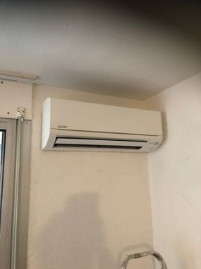 Climatiseur mural au-dessus d'une fenêtre dans une pièce.