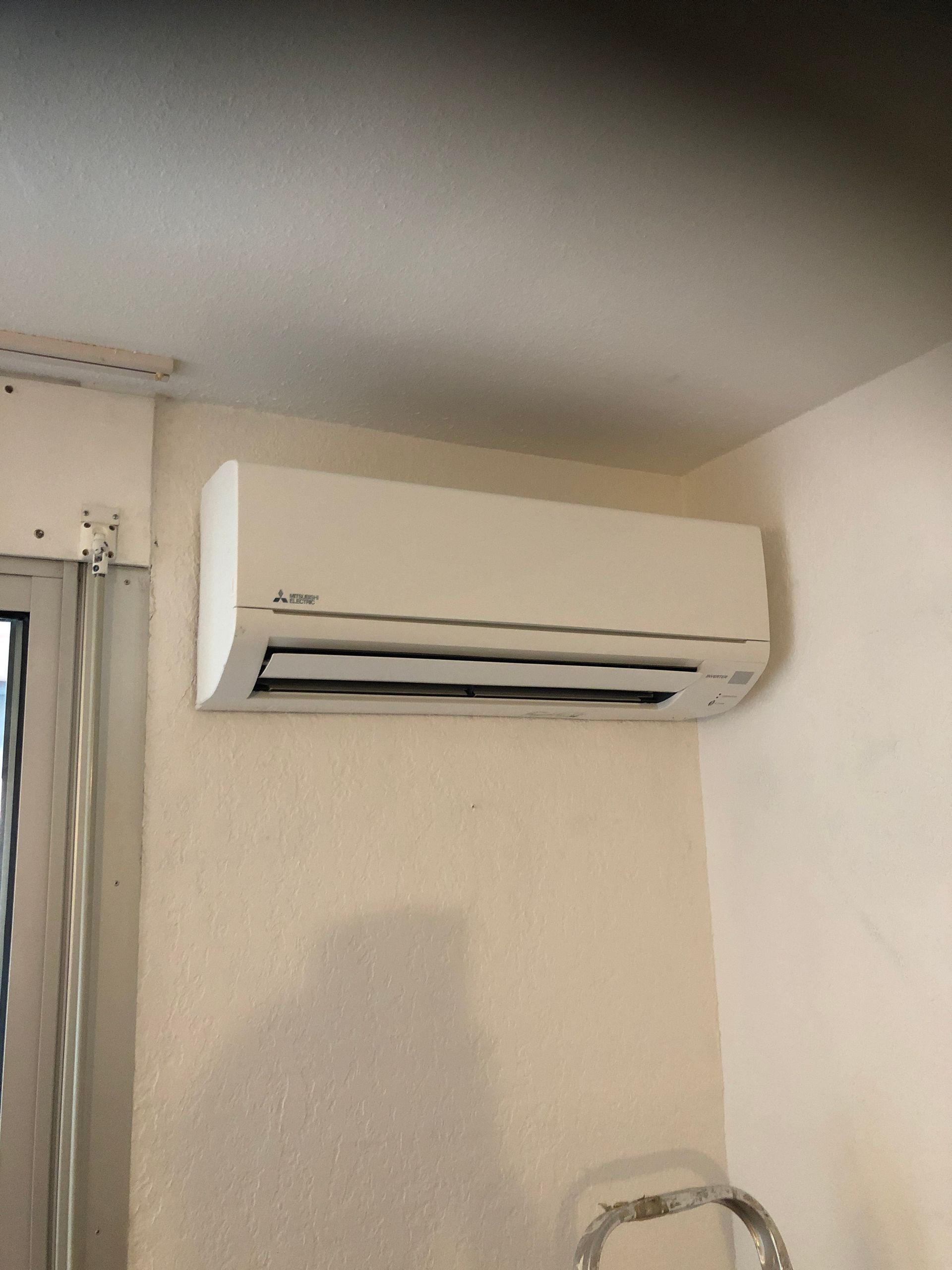 Climatiseur mural au-dessus d'une fenêtre dans une pièce.