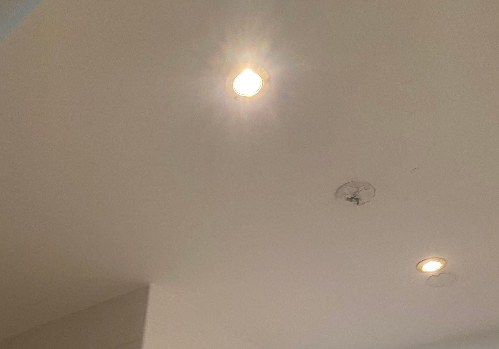 Plafond avec deux spots encastrés et un détecteur de fumée près de l'angle.