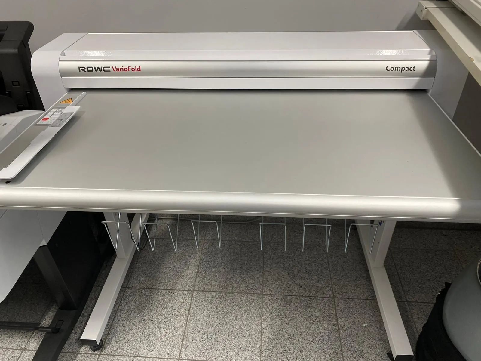 Ein weißer Tisch mit einer Maschine darauf, auf der steht „Grand