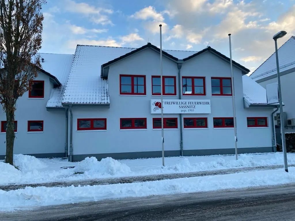 Ein großes weißes Gebäude mit roten Fenstern ist schneebedeckt.