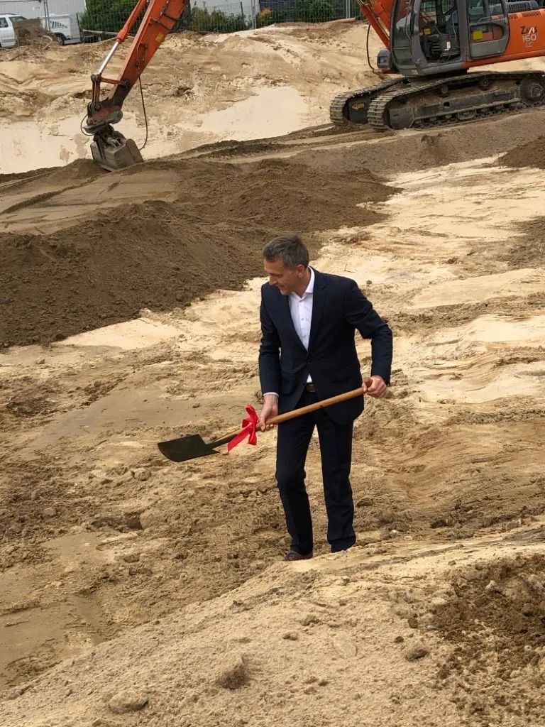 Ein Mann im Anzug gräbt mit einer Schaufel im Dreck.