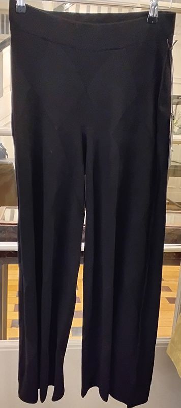 Schwarze Hose mit weitem Bein hängt auf einem Kleiderbügel.