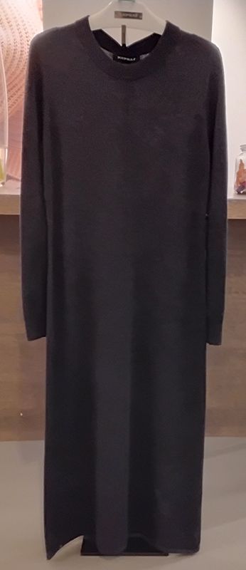 Ein langes, dunkelgraues Strickkleid auf einem Kleiderbügel. Es hat lange Ärmel und einen geschlitzten Saum.