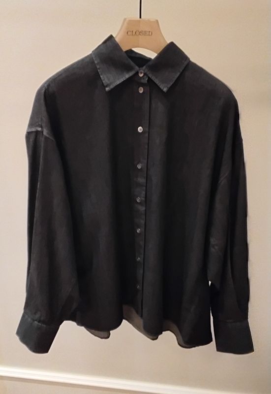 Dunkelgraues, übergroßes Button-Down-Hemd auf einem Kleiderbügel.