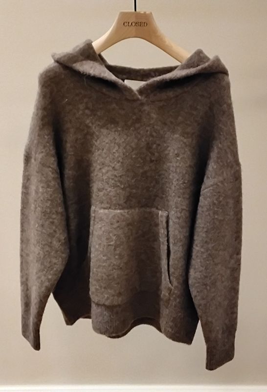 Braunes Kapuzensweatshirt mit Kängurutasche, das an einem Holzbügel hängt.