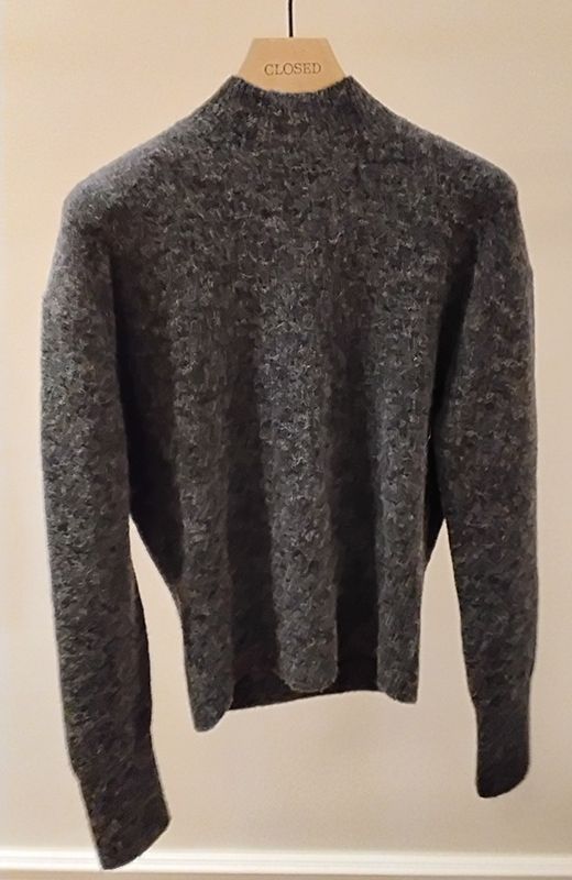 Grau gesprenkelter Pullover auf einem hölzernen Kleiderbügel.